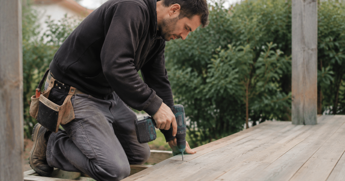 Ouvrier fixant planches bois horizontales sur structure terrasse