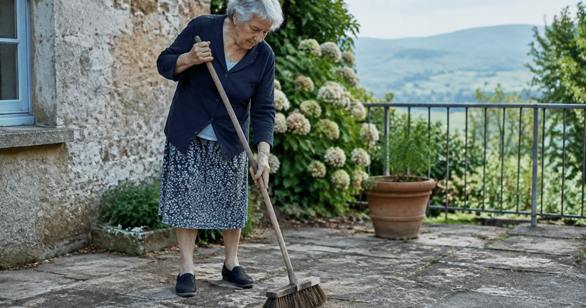 Femme agee brossant pierre terrasse avec balai dur