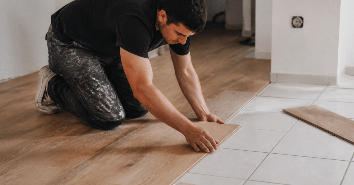 Ouvrier posant lames bois sur sol carrelage blanc