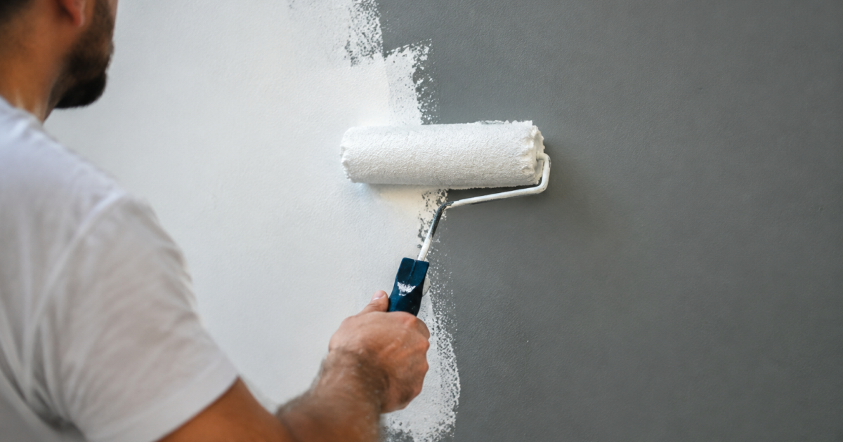 Rouleau appliquant produit blanc sur mur gris
