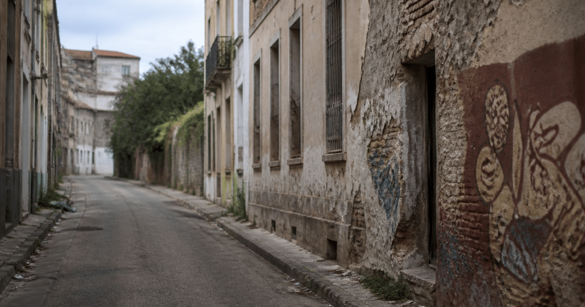 Rue urbaine déserte avec immeubles délabres et graffitis visibles