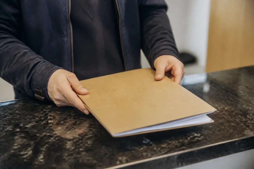 Mains tenant une chemise cartonnee sur un comptoir