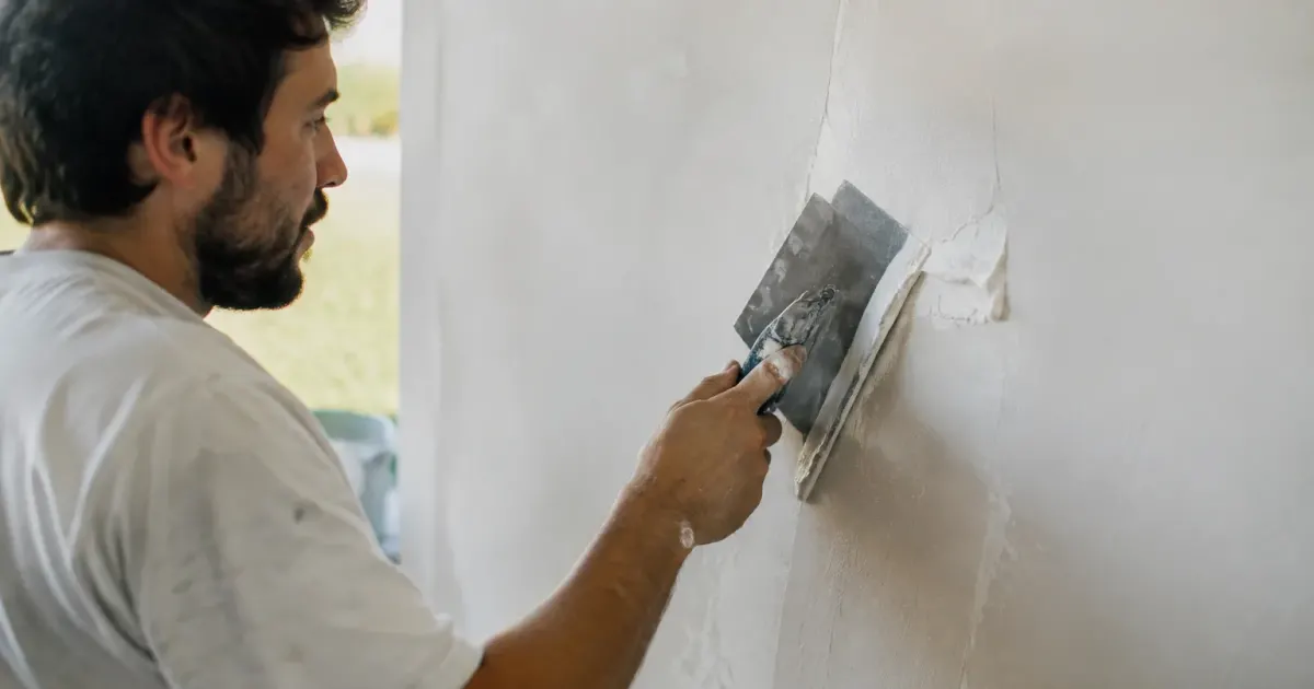 Truelle lissant une couche blanche sur un mur plat