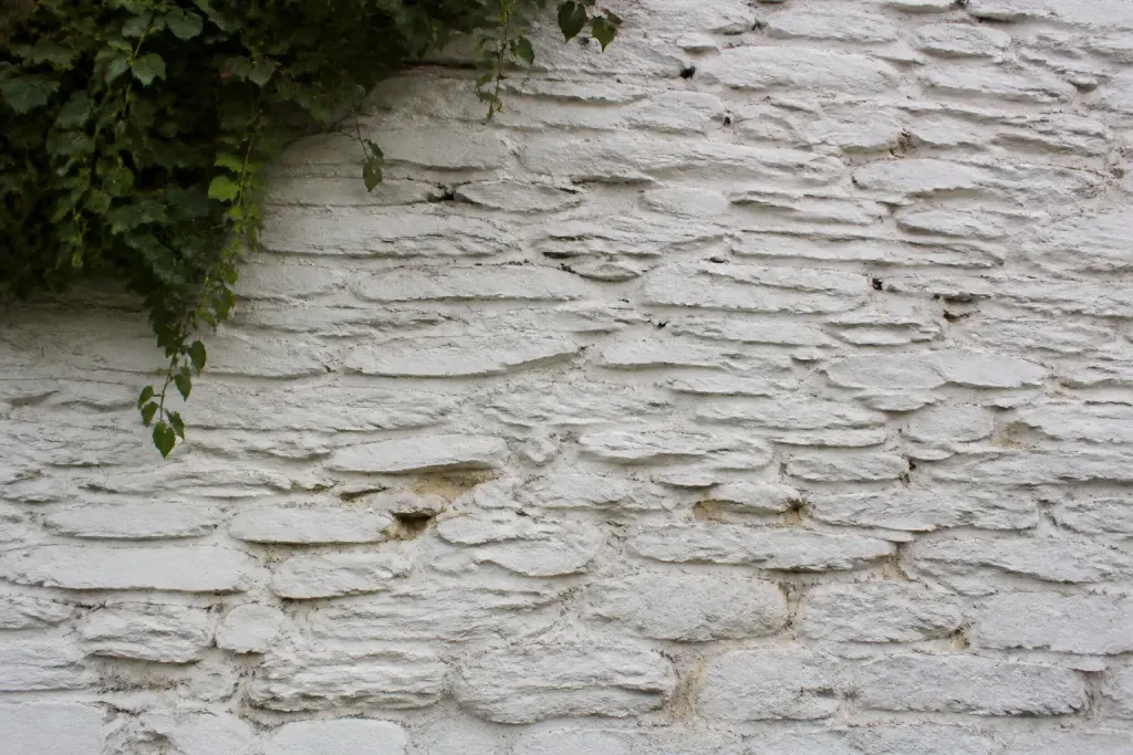 Vieux mur en pierre avec enduit blanc en lamelles